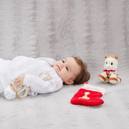 Zdjęcie poglądowe Sophie la Girafe Mon premier Noël – dziecko obok żyrafy, pluszowej zabawki i czerwonej skarpety